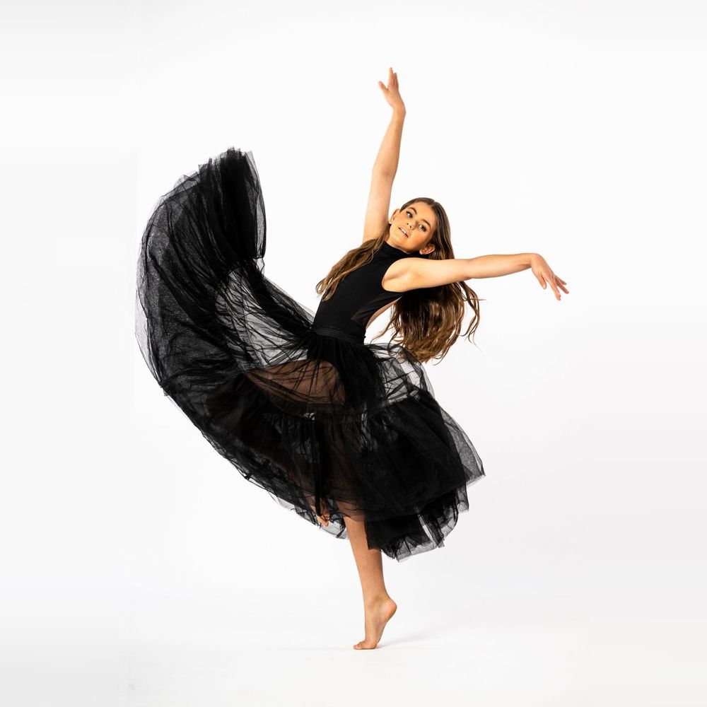 Dancer in a flowing black tulle skirt, arms raised